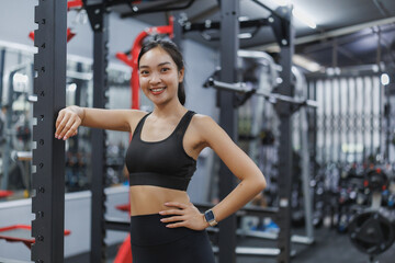 Young asian woman smiling and posing in a modern gym