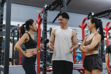 Fitness instructor explaining exercises to two women in a gym