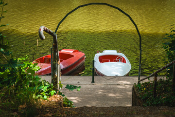 Peaceful boats resting by a tranquil lake surrounded by lush greenery during a sunny summer...