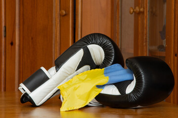 Black and white boxing gloves and Ukrainian flag lie on the table in the bedroom, gloves for boxing