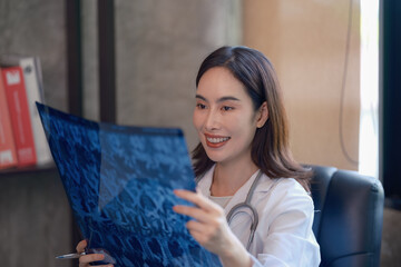 An Asian female doctor holding and checking a lung x-ray film at a hospital.