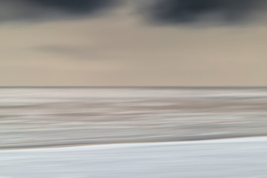 Blurred motion abstract seascape at dusk with grey clouds and faint pink light