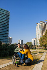 Mother playing with son with disability in wheelchair in city park