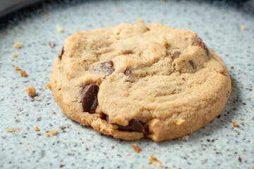 A closeup view of a chocolate chip cookie, on a plate.