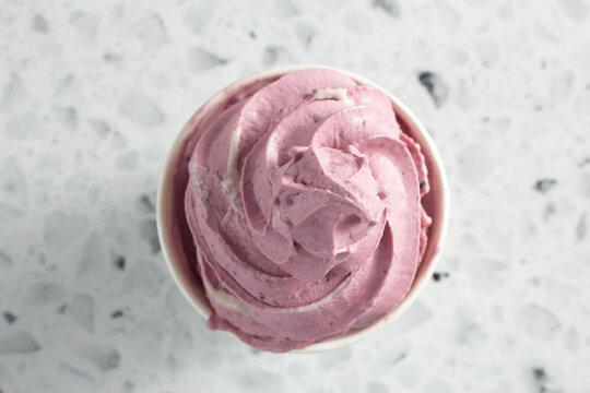 A top down view of a mixed berry soft serve ice cream, in a cup.