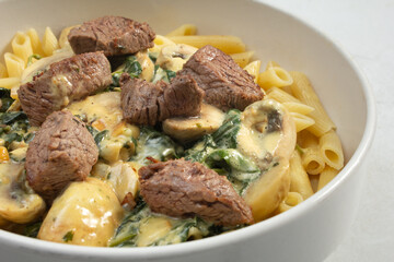 A view of filet mignon over penne.