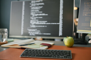 Closeup showing wireless keyboard on desk with notebook, pen, green apple, glass of water and...