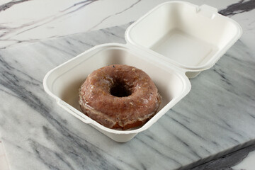 A view of a donut in a to go container.