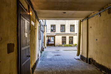 Historic courtyard passage with archway in old city district, pedestrian walking through narrow...
