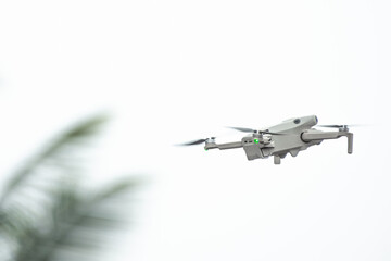 Drone with camera flies in the background of trees and sky. The drone hovers in the air and records