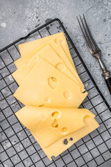Maasdam cheese slices on kitchen table. grey background. top view