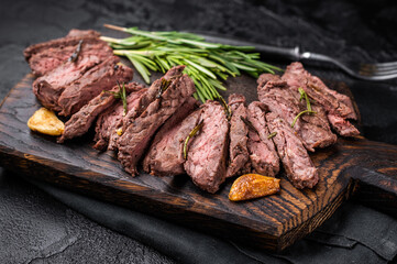 Roast Skirt Machete Steak, grilled beef meat on cutting board. black background. top view
