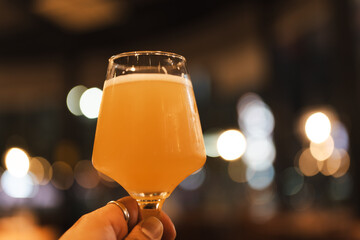Close up of a golden beer in a glass with foam bubbles, highlighting refreshing cold beverage for...