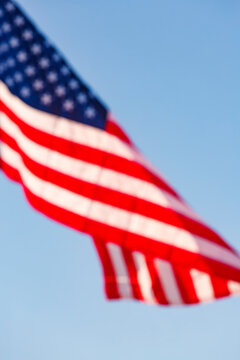 A large stars and stripes flag, the American flag fluttering in the breeze, in a blue sky.