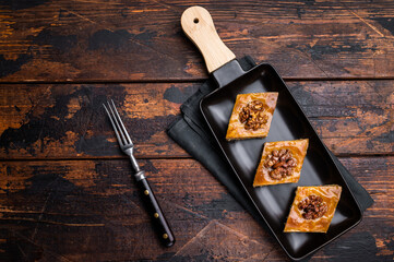 Homemade Walnut Baklava with honey on plate. wooden background. top view