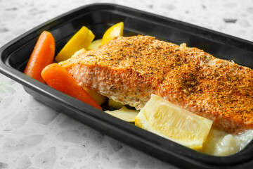 A view of an entree of blackened salmon, in a container.