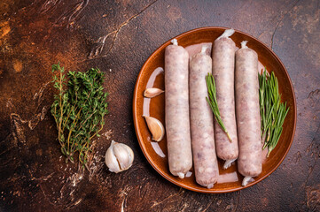 Raw Sausages with forcemeat mincemeat with herbs in plate. brown background. top view
