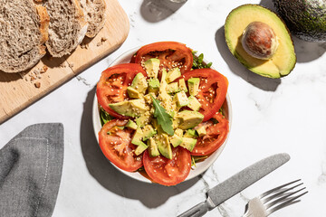 Top view of avocado and tomato salad on kitchen countertop background