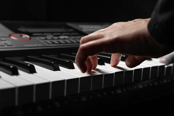 A pair of hands with long slender fingers gently presses down on the white keys of a digital piano...