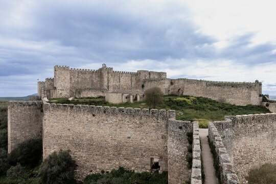 Long walls protecting medieval castle under cloudy sky
