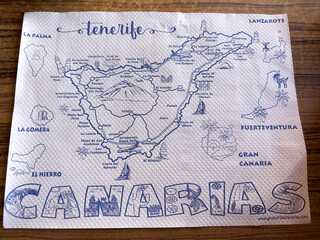An illustrated map of the Tenerife and Canary Islands on a white napkin with descriptions of each island, places and landmarks highlighted, showcasing the region's unique geography and culture. © Olga