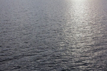 Sunlight on the ocean, a ray of sunlight on the grey water surface.