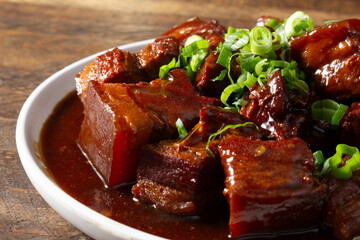 A closeup view of an entree of braised pork belly in brown sauce.