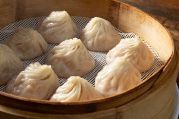 A closeup view of a bamboo steamer containing xiaolongbao.