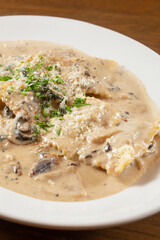 A closeup view of a plate of ravioli in a mushroom cream sauce.