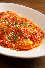 A closeup view of a plate of ravioli in marinara sauce.