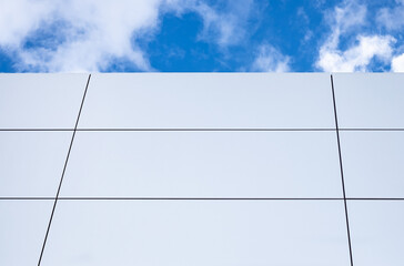 Top of the concrete building against the blue sky and white clouds. Modern architecture.