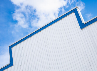Top of the wooden building against the blue sky and white clouds. Modern architecture.