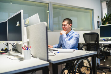 Confident entrepreneur using computer at desk in modern workplace, showing determination and...