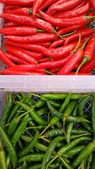 Fresh red chilies and green chilies in plastic boxes sell at traditional market.