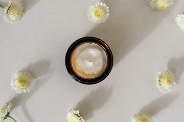 Cosmetic cream in container for face and body skin care top view. Natural organic product in glass jar for wellness, beauty and spa.