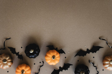 Halloween holiday mockup with party decorations of pumpkins, bats on gold background top view. Happy halloween greeting card in flat lay style.