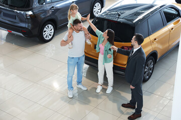 Salesman giving car key to happy family in salon