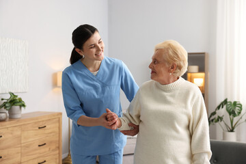 Obraz premium Nurse assisting senior woman indoors. Home health care service