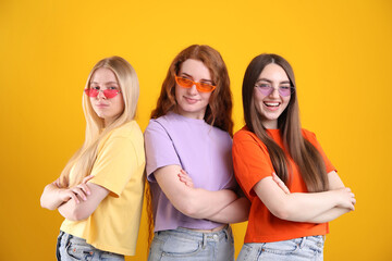 Beautiful women with different hair colors wearing stylish sunglasses on orange background