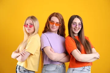  Beautiful women with different hair colors wearing stylish sunglasses on orange background © New Africa