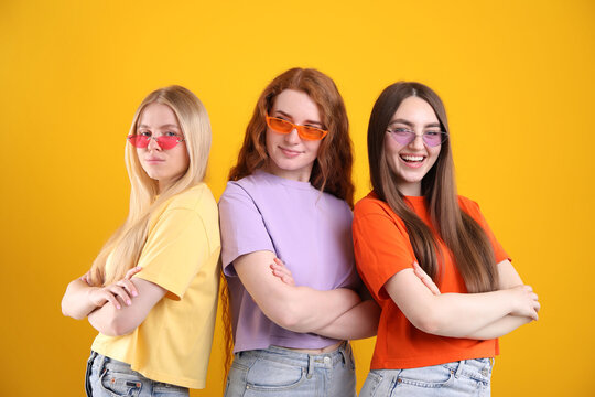 Beautiful women with different hair colors wearing stylish sunglasses on orange background