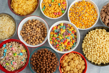 A top down view of bowls of assorted popular cereals.