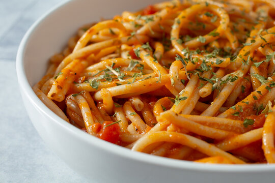 A closeup view of a bowl of gluten-free bucatini in pasta sauce.