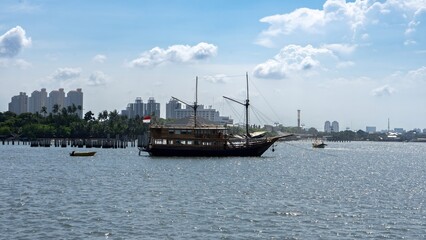 Traditional Indonesian Phinisi Ship in Jakarta Bay with Modern City Skyline