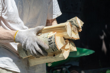 A person carries a stack of freshly cut firewood, ready to use.
