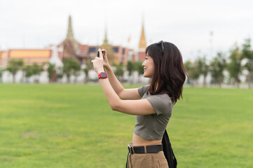 Happy southeast asian woman teenager blogger world explorer on solo travel. Take photo with...
