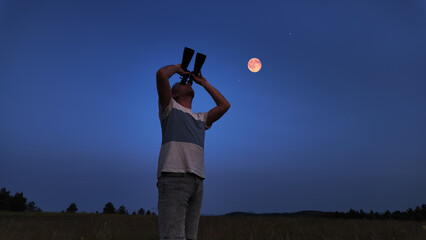 Amateur astronomer using binoculars for watching stars, Moon, planets and other celestial objects...