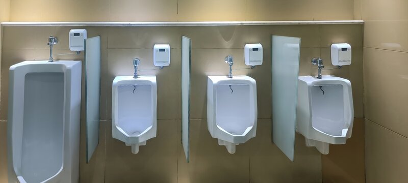 Row of modern urinals with automatic flush sensors in a public restroom.