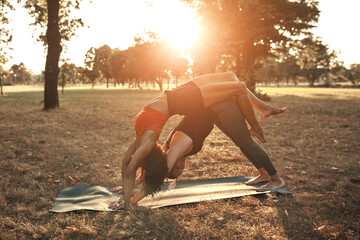 Two women practicing yoga and stretching in the park on a hot sunny summertime day.