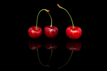 Fresh cherries on a black background with reflection. 
